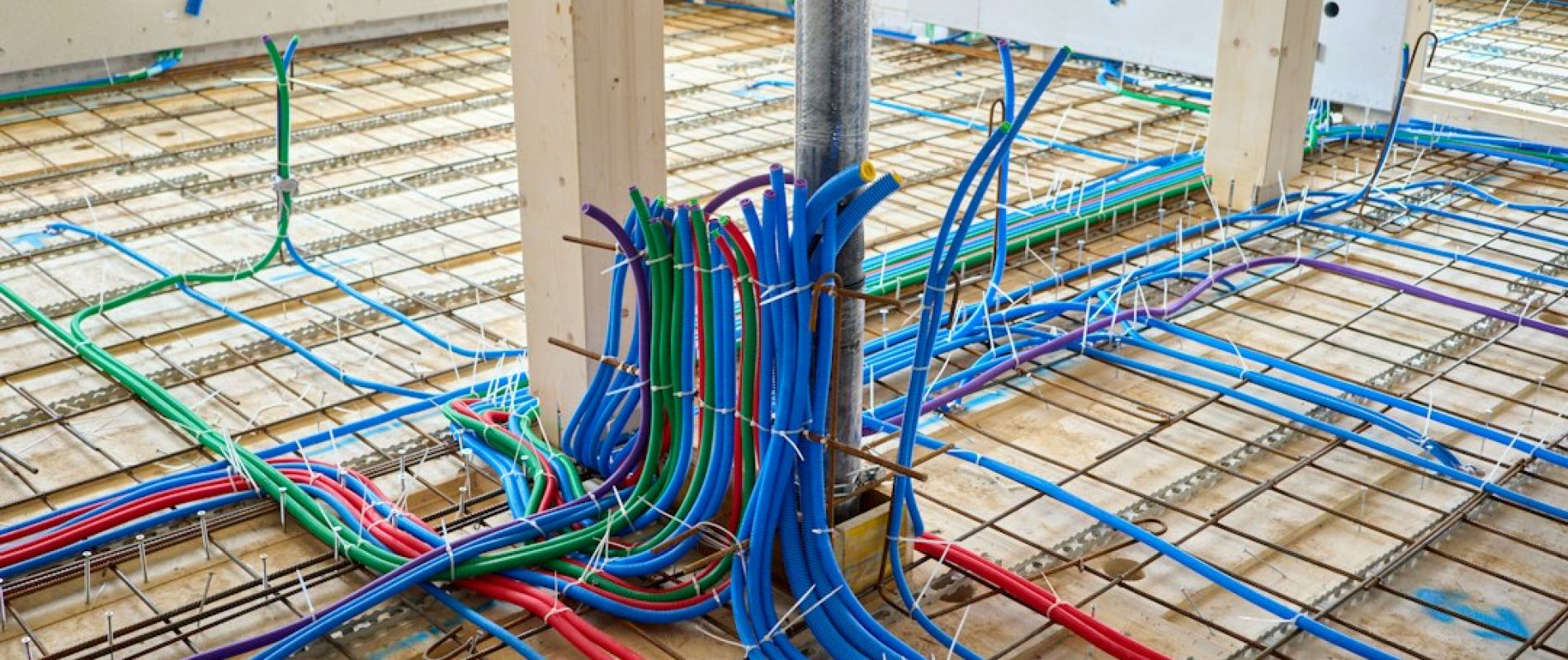 Instalación de tuberías de suelo radiante con mangueras azules, rojas y verdes sobre malla metálica en construcción
